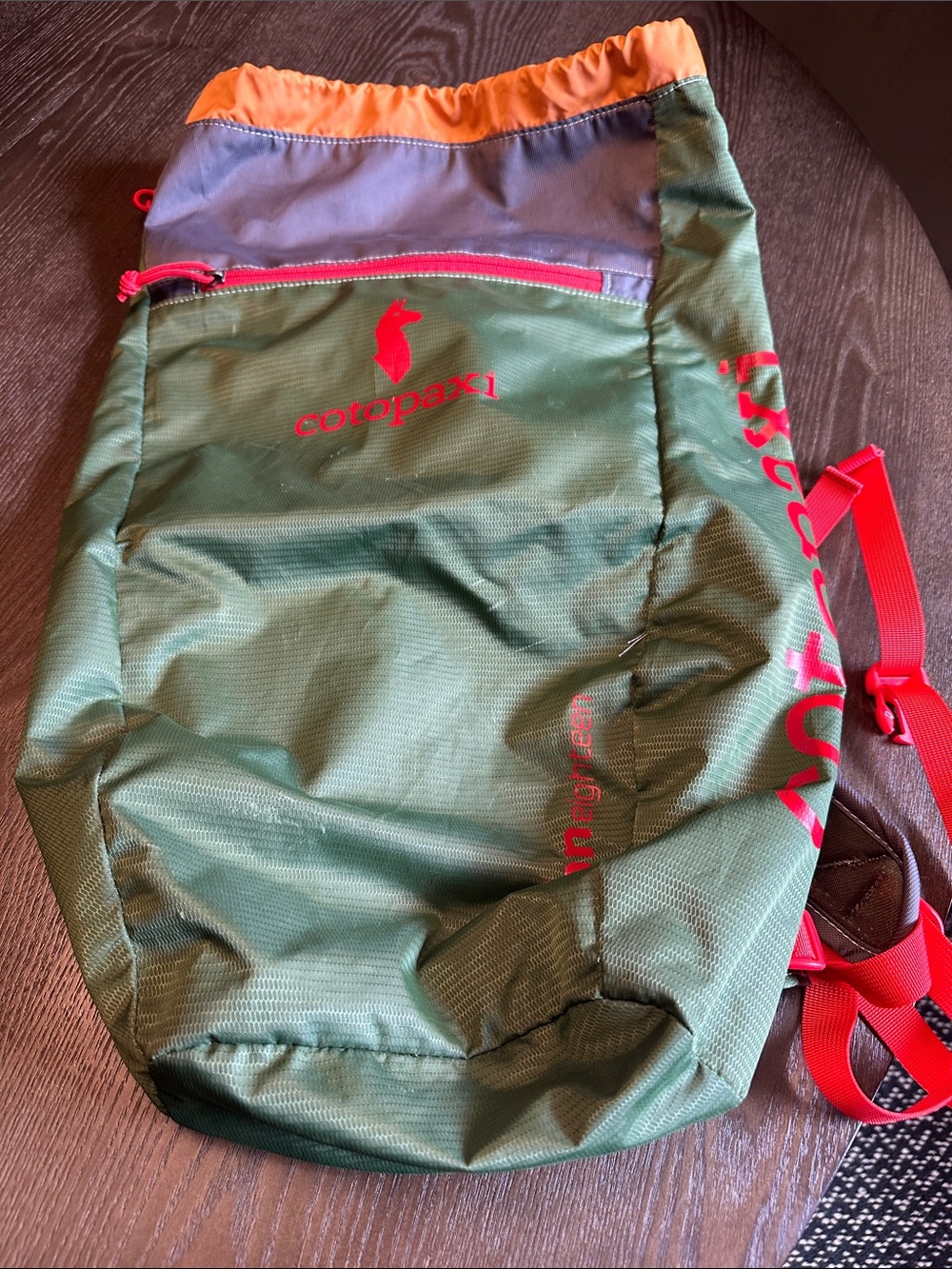 cotopaxi green daypack with orange trim and pink accents